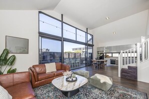 A spacious living area with a large window, a leather sofa, a marble coffee table, and a staircase leading to an upper level. - Fun for Families: Location, Cinema, Games, Wifi (Leederville)