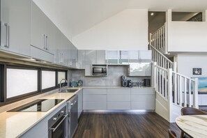 A modern kitchen with grey cabinets, a stainless steel range, and a built-in microwave. - Fun for Families: Location, Cinema, Games, Wifi (Leederville)
