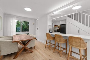 Una cocina moderna con armarios blancos, una mesa de comedor de madera y taburetes de mimbre.