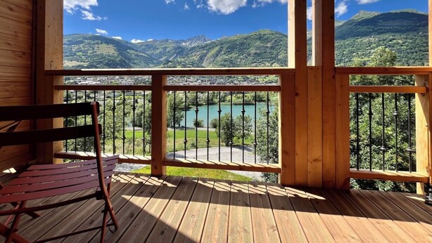 Eine Holzterrasse mit Blick auf Berge und einen See.