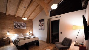 Ein Schlafzimmer mit Holzboden, einem Bett, einem Sessel und Bildern an den Wänden.