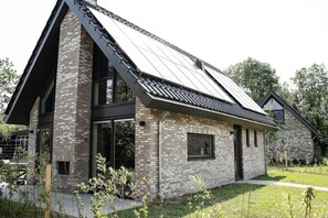 Uma casa moderna com telhado inclinado, janelas grandes e fachada de tijolos.