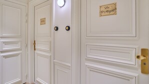A set of white doors with nameplates and a light fixture. - Sublim AC Apartment 3 Bdr Saint Germain des Prés (Paris)
