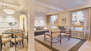 A modern living room with a dining area, large windows, and a view of the city. - Sublim AC Apartment 3 Bdr Saint Germain des Prés (Paris)