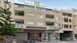 Ein mehrgeschossiges Gebäude mit Balkonen, einem Eingang im Erdgeschoss und einem Fahrradstellplatz.