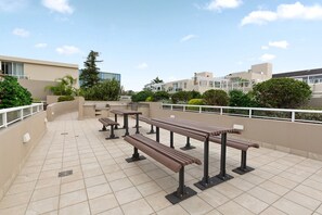 A rooftop terrace with multiple wooden benches, a tiled floor, and a railing. - Spacious 1 Bed Near Manly Beach (Manly)