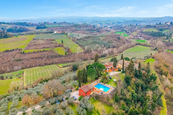 Uma villa com piscina, cercada por campos em socalcos e árvores.