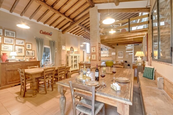 A dining area with wooden furniture, a kitchen area with a brick wall, and a sign that reads 'Cuisine'. - Torre Rasa Agriturismo Apartments (Castelfiorentino)