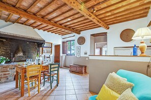 A rustic interior with a dining area, wooden ceiling beams, a fireplace, and a cozy seating area. - Torre Rasa Agriturismo Apartments (Castelfiorentino)