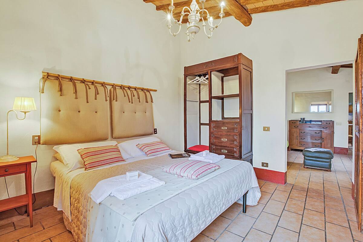 A bedroom with a bed, bedside table, lamp, and a wooden wardrobe.