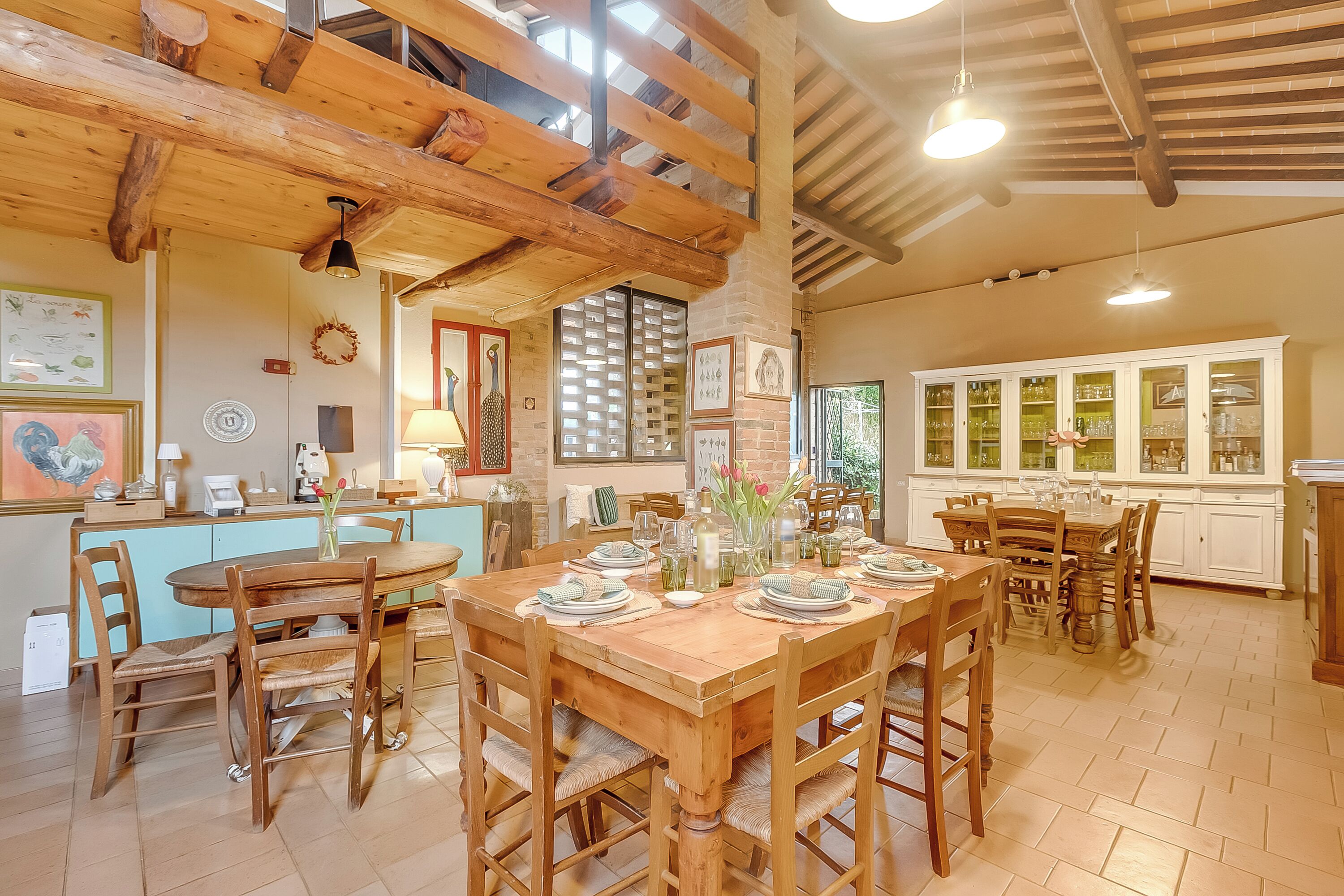 Una mesa de comedor de madera con sillas, una cocina con armarios blancos y una estructura de techo de madera.