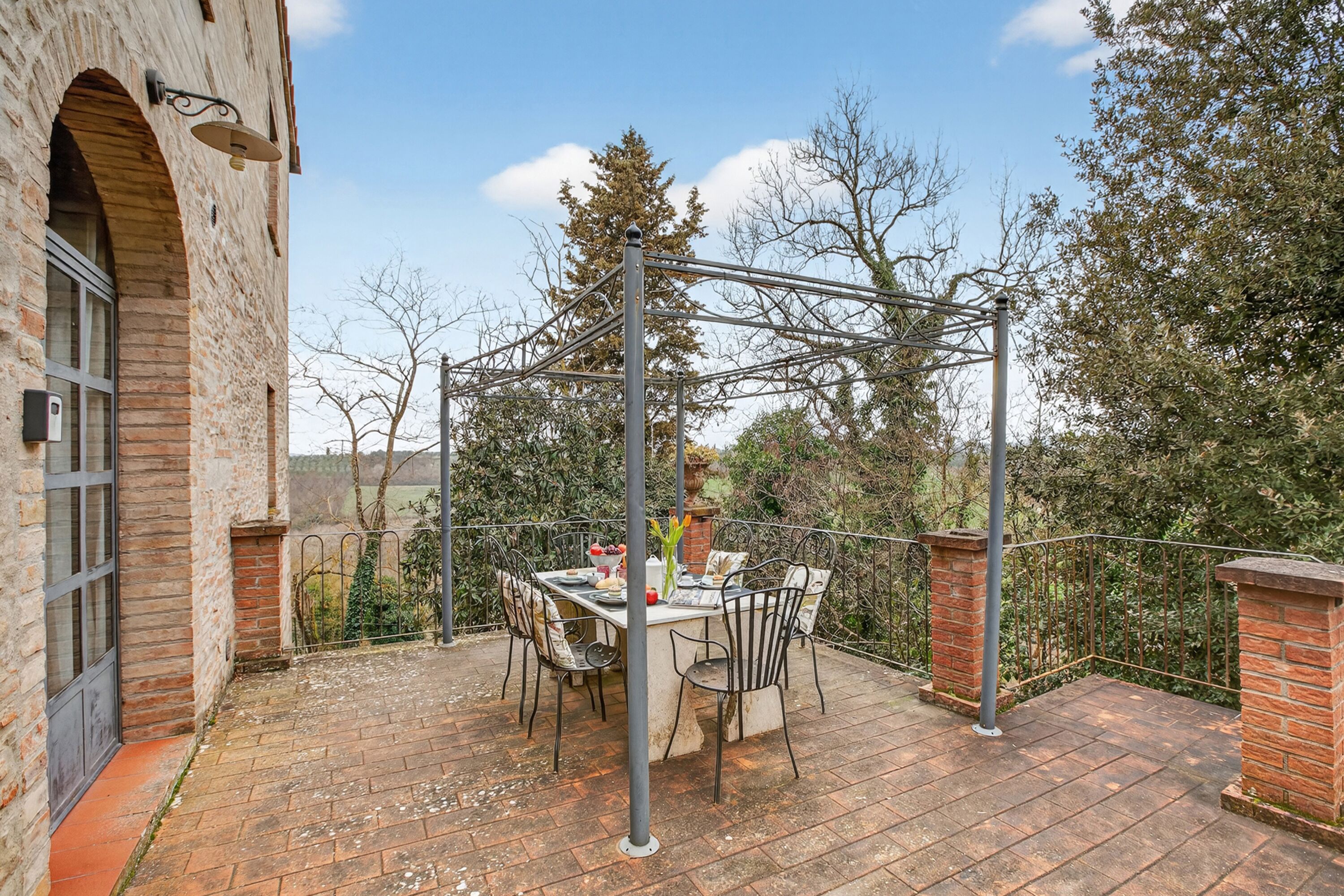 Un patio con una mesa y sillas, una pérgola y un muro de ladrillo.