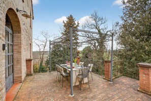 A patio with a table and chairs, a pergola, and a brick wall.