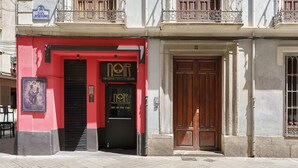 A building with a red facade, a black door, and a balcony with ornate railings. - San Jeronimo Suite. Free Parking (Granada)