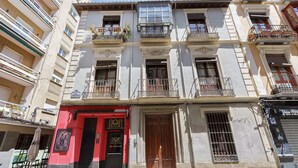 A multi-story building with balconies, a red door, and a window with bars. - San Jeronimo Suite. Free Parking (Granada)