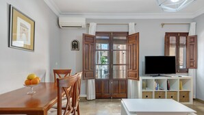 A dining area with a wooden table and chairs, a white console table with a flat-screen TV, and a bookshelf. - San Jeronimo Suite. Free Parking (Granada)