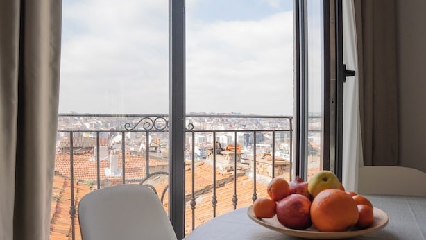 A balcony with a table holding a fruit bowl, a chair, and a view of a cityscape. - Stylish Duplex with Private Terrace & Golden Horn View – 5 min to Istiklal (İstanbul)