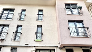 A multi-story building with a central entrance featuring ornate metal gates, multiple balconies with black railings, and a tiled pavement in front. - Stylish Duplex with Private Terrace & Golden Horn View – 5 min to Istiklal (İstanbul)