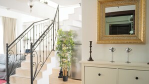 A staircase with a metal railing, a potted plant, and a cream-colored dresser with a mirror. - Stylish Duplex with Private Terrace & Golden Horn View – 5 min to Istiklal (İstanbul)