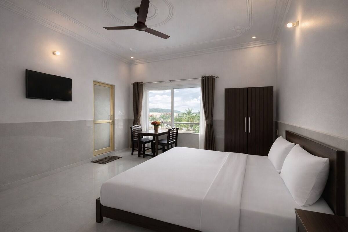 Habitación de hotel con cama, televisor, mesa de comedor y vistas al exterior.