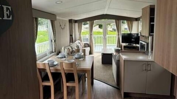 A caravan kitchen with a dining area, a TV, and a view of the outdoors. - Tattershall Lakes Country Park - Holiday Accommodation 15201 (Lincoln)