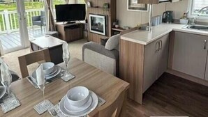 A compact kitchen with a microwave, a sink, and a dining area with a table set for two. - Tattershall Lakes Country Park - Holiday Accommodation 15201 (Lincoln)