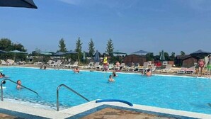 A swimming pool with lounge chairs and umbrellas, surrounded by trees and buildings. - Tattershall Lakes Country Park - Holiday Accommodation 15201 (Lincoln)