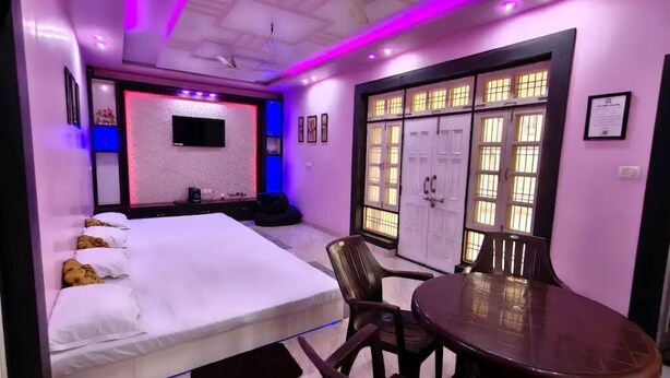 A bedroom with a bed, a TV, a desk, and a chair. - Cozy Nirmala House Homestay in Varanasi (Varanasi)