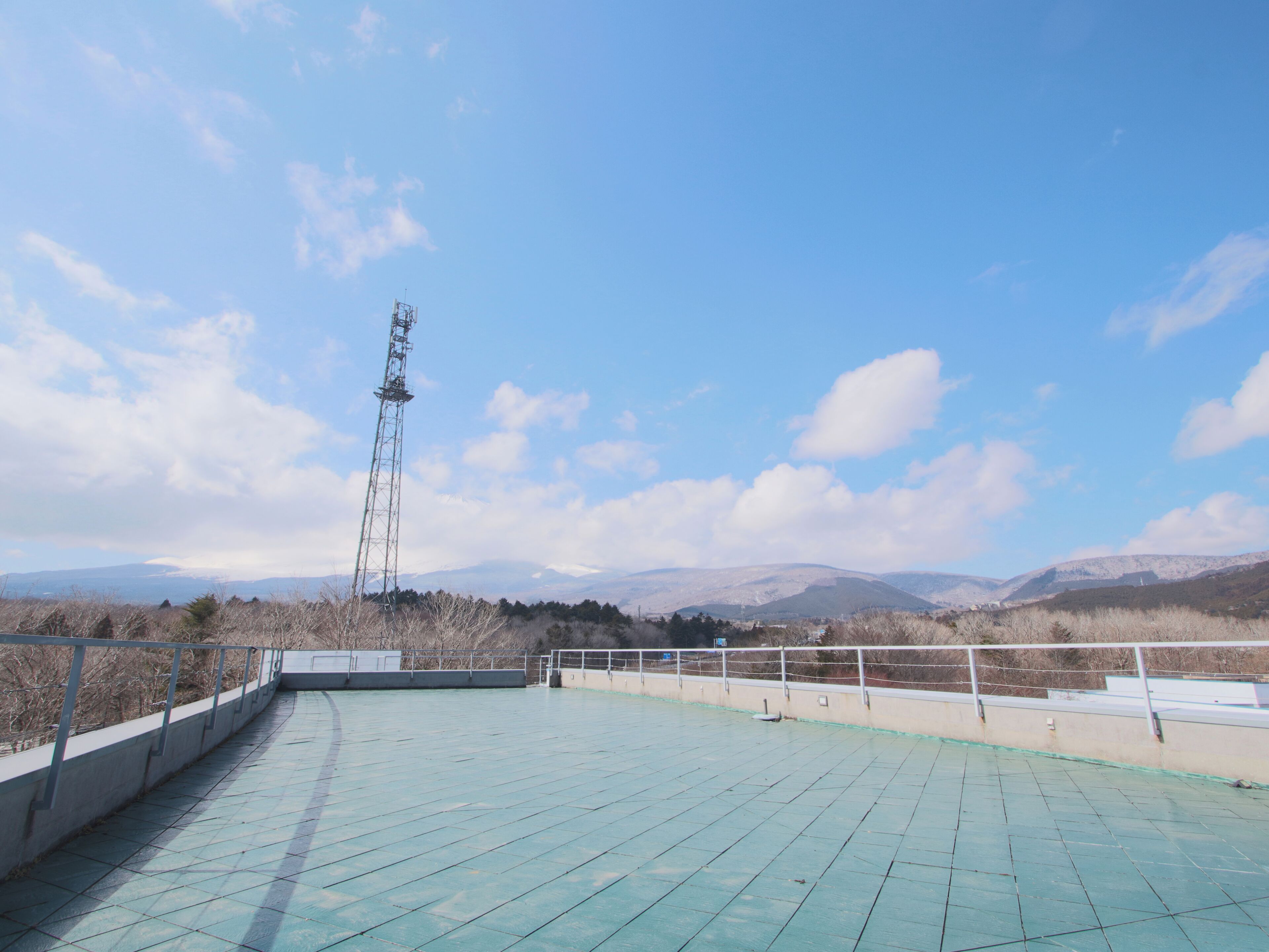 Terraço no telhado com vista desobstruída para montanhas distantes e uma torre de comunicação.