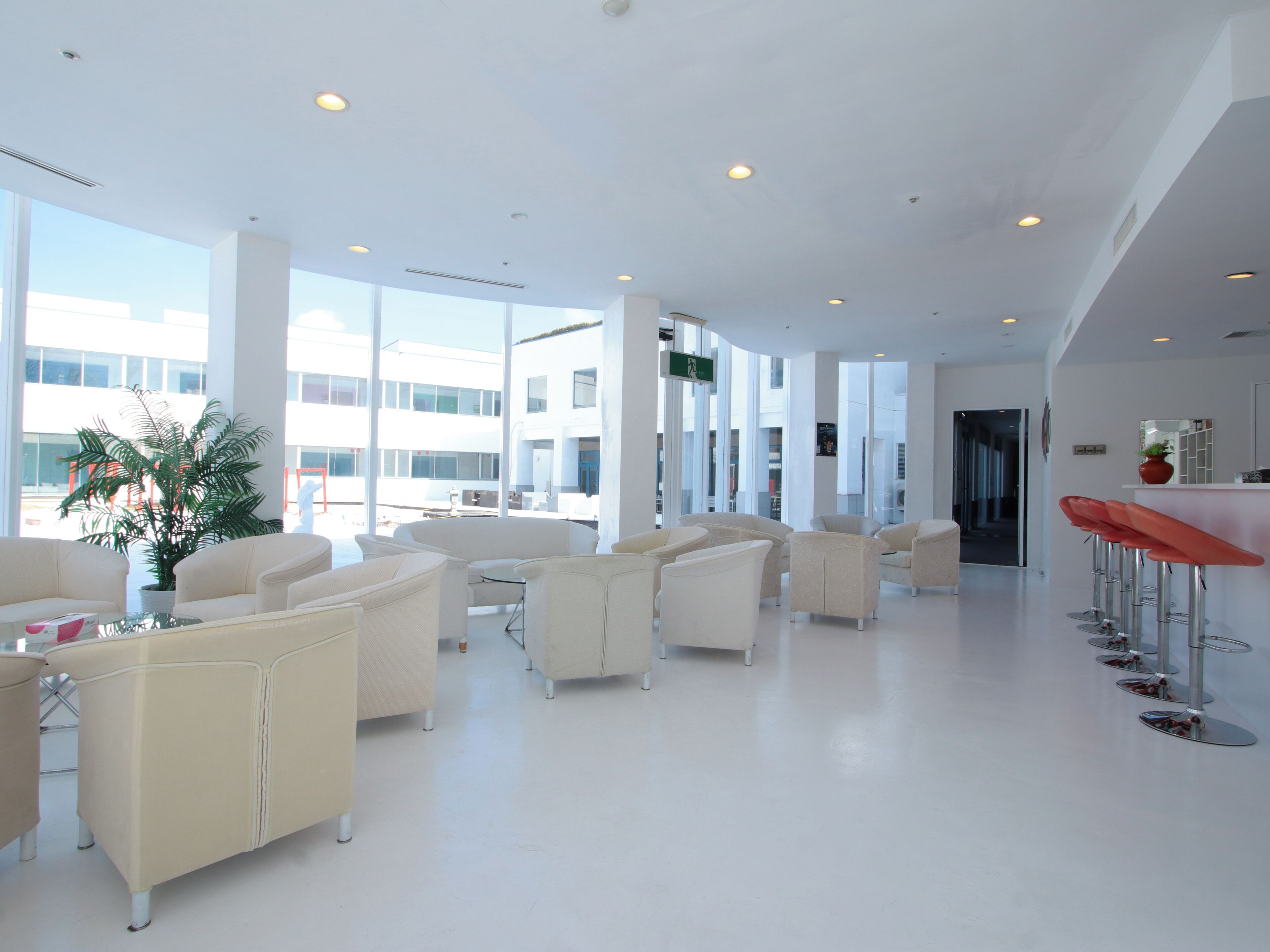 A spacious lobby with high ceilings, large windows, and a modern bar area.