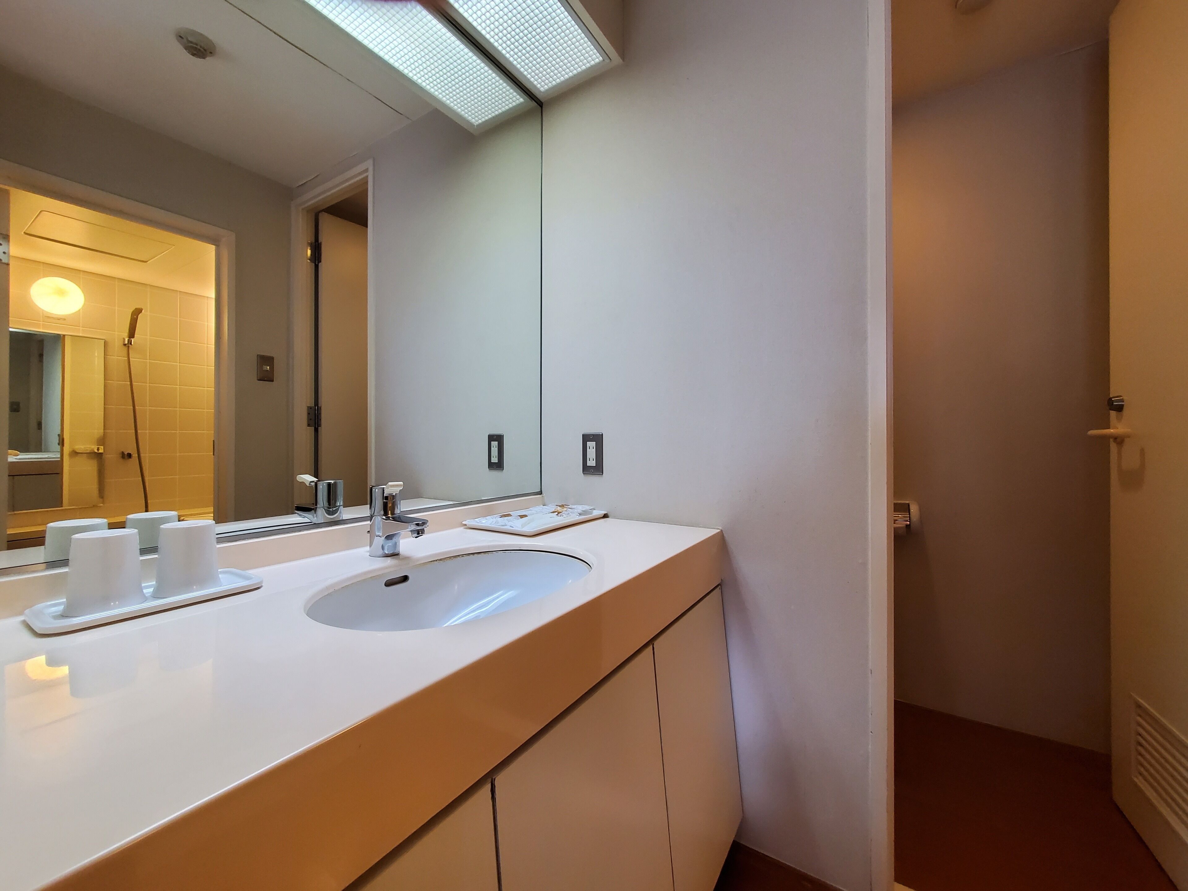 Een badkamer met een wit wastafelmeubel, een spiegel en een douche.