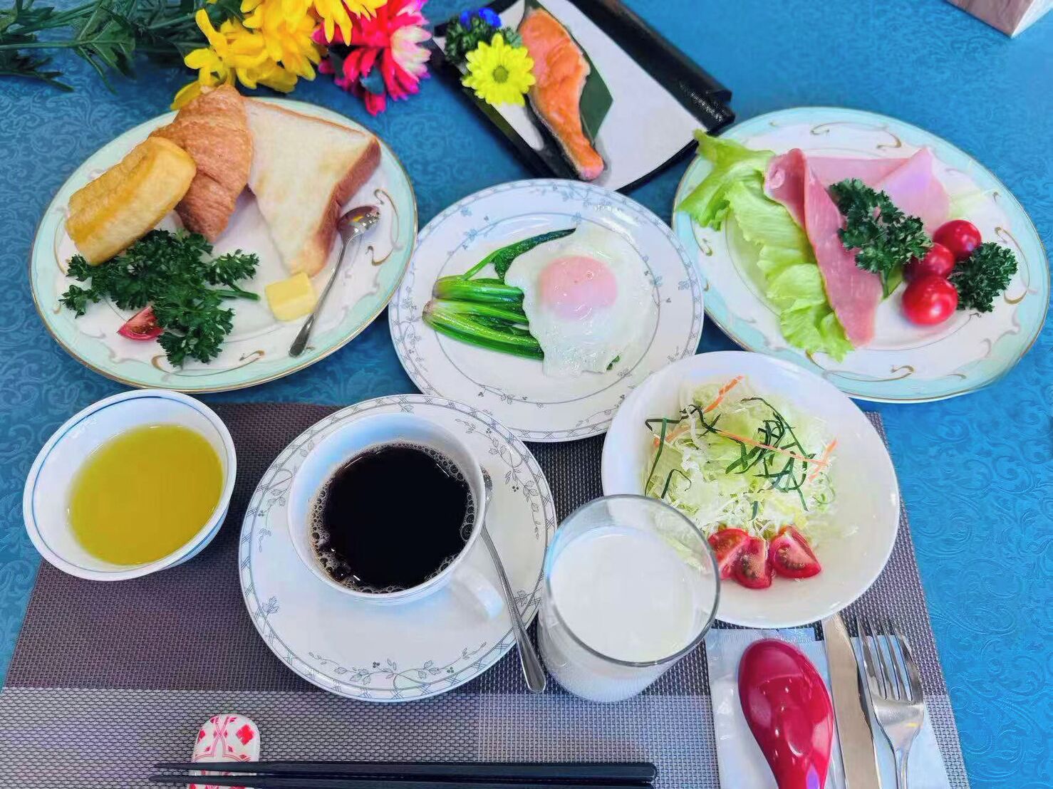 A table with plates of food, a cup of coffee, and a glass of milk.