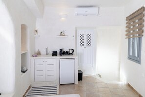 A compact kitchen with white cabinetry, a built-in refrigerator, and a coffee maker. - Panoramic Cave Suite with outdoor Hot Tub and Caldera View (Thira - Santorini)