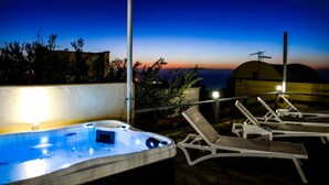 Un área de piscina en la azotea con jacuzzi y sillones de descanso.