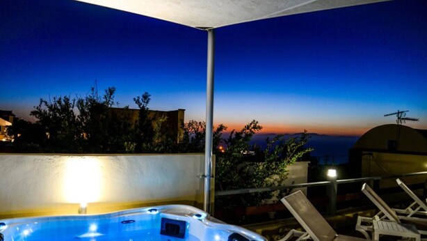 Un jacuzzi con vista al atardecer, sillones de descanso y una estructura de soporte.
