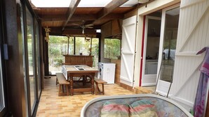 A covered patio with a wooden table, chairs, a sofa, and a washing machine. - House 400 m from the beach and port, 5 people (Saint-Michel-Chef-Chef)