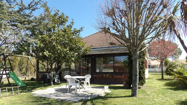 A patio area with a table and chairs, a brick wall, and a green slide. - House 400 m from the beach and port, 5 people (Saint-Michel-Chef-Chef)
