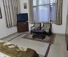 A living room with a sofa, a coffee table, a TV, and patterned curtains.