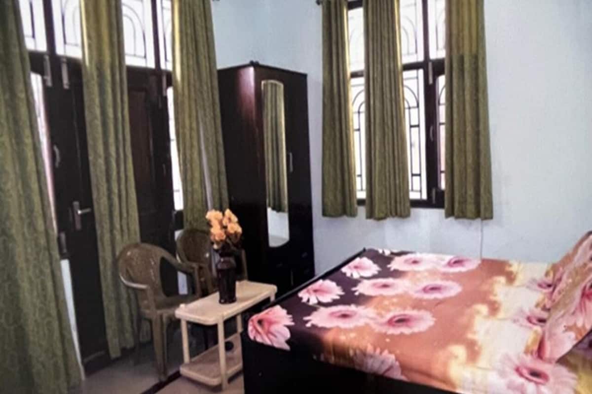 A bedroom with a bed, a desk, a chair, a wardrobe, and curtains.