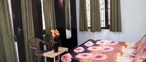 A bedroom with a bed, a desk, a chair, a wardrobe, and curtains.