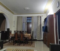 A dining area with a table and chairs, a television, and a cabinet.