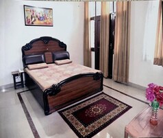A bedroom with a bed, a nightstand, a mirror, a door, and a window.