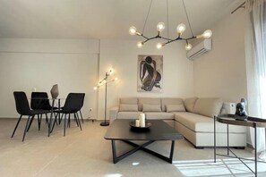 Un salon moderne comprenant un canapé, une table basse, une table à manger avec des chaises et un luminaire suspendu.