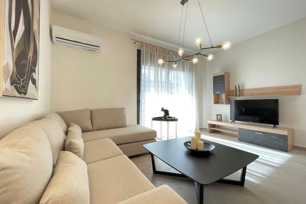 Un soggiorno moderno con un divano, un tavolino, una TV e un lampadario.