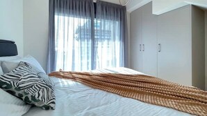 Ein Schlafzimmer mit Bett, Vorhängen, einer Klimaanlage und einem Kleiderschrank.