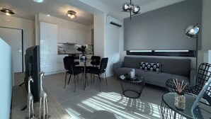 Ein modernes Wohnzimmer mit einer Couch, einem Couchtisch und einem Essbereich mit Stühlen und einem Tisch.