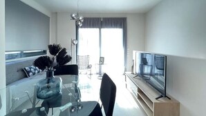 Ein modernes Wohnzimmer mit einem Glastisch, einem Flachbildfernseher und einer Couch.