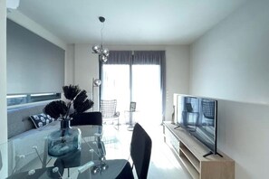 Una sala moderna con una mesa de vidrio, un televisor de pantalla plana y un sofá.