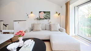 A modern living room with a sofa, a coffee table, and a painting on the wall. - The Abbey Mews House (London)