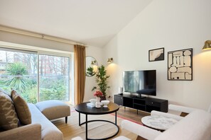 Een moderne woonkamer met een bank, een ronde tafel, een televisie en kunst aan de muur.